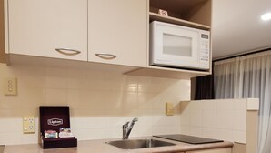 Una cocina compacta equipada con lavavajillas, microondas y pileta. Se exhiben tés Lipton en la encimera.