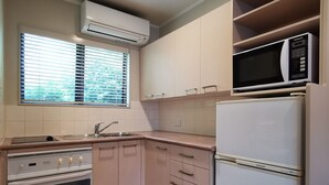 Una cocina con horno empotrado, microondas y refrigerador.