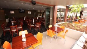 A restaurant with indoor and outdoor seating, including tables and chairs, and a small garden area. - Peden's Hotel (Cessnock)