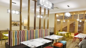Een restaurant met gestreepte zitplaatsen, tafels en kleurrijke krukken.