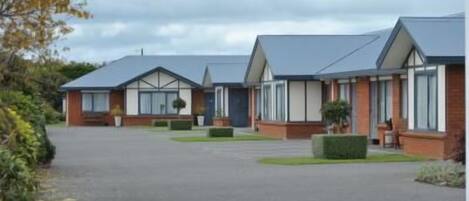 A row of modern, single-story buildings with flat roofs, arranged in a linear fashion along a paved driveway.