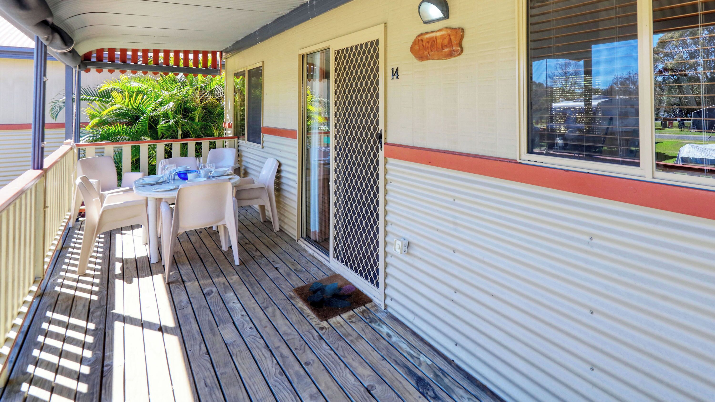 A covered outdoor area with a table set for dining, a door, and a window with a view of the outside.