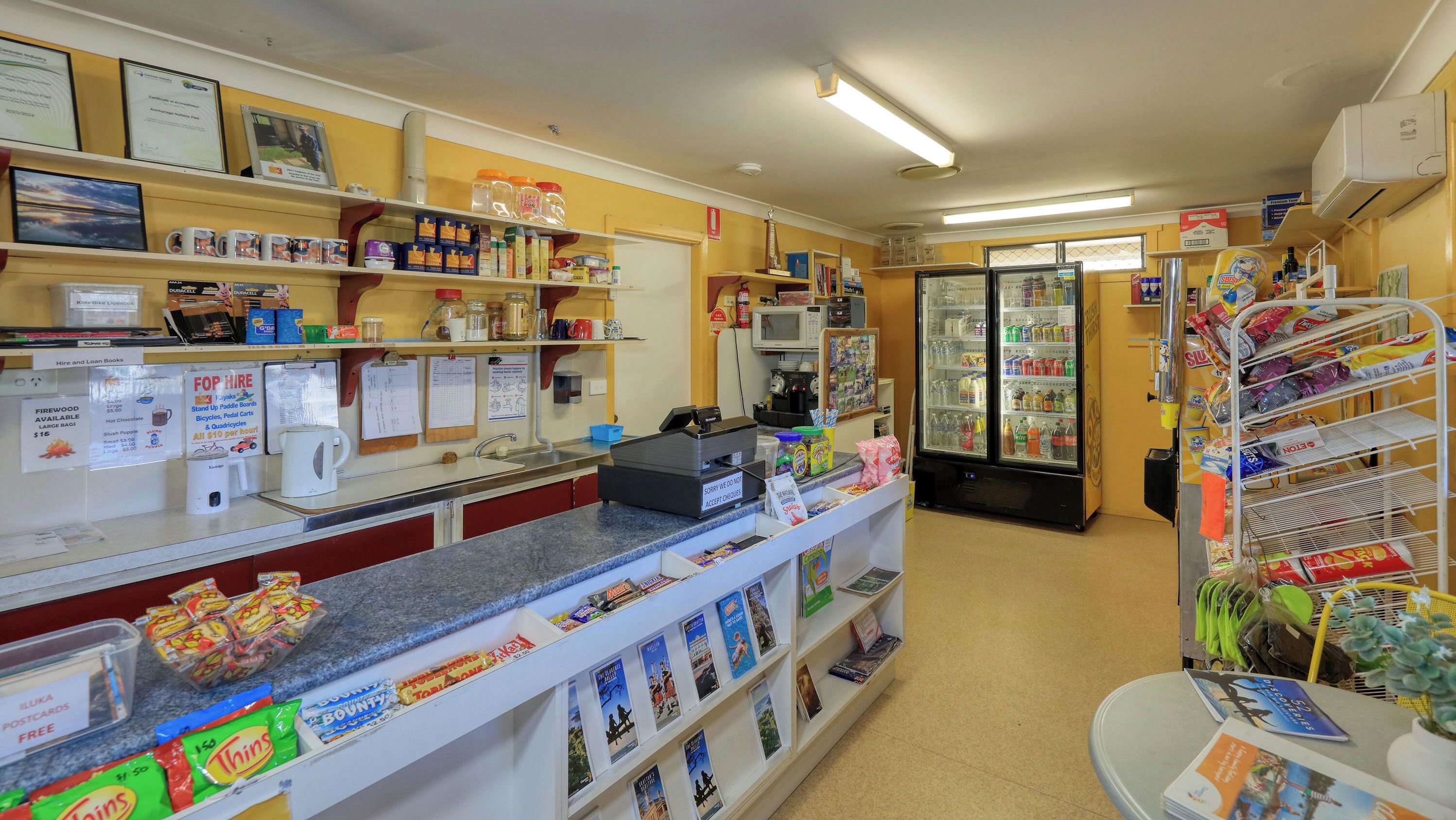 A small, well-organized convenience store with a variety of snacks, beverages, and household items on shelves and counters.