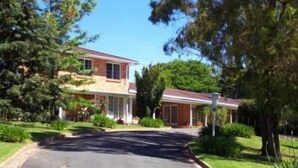 Una casa de dos pisos con un porche delantero, rodeada de exuberante follaje y árboles.