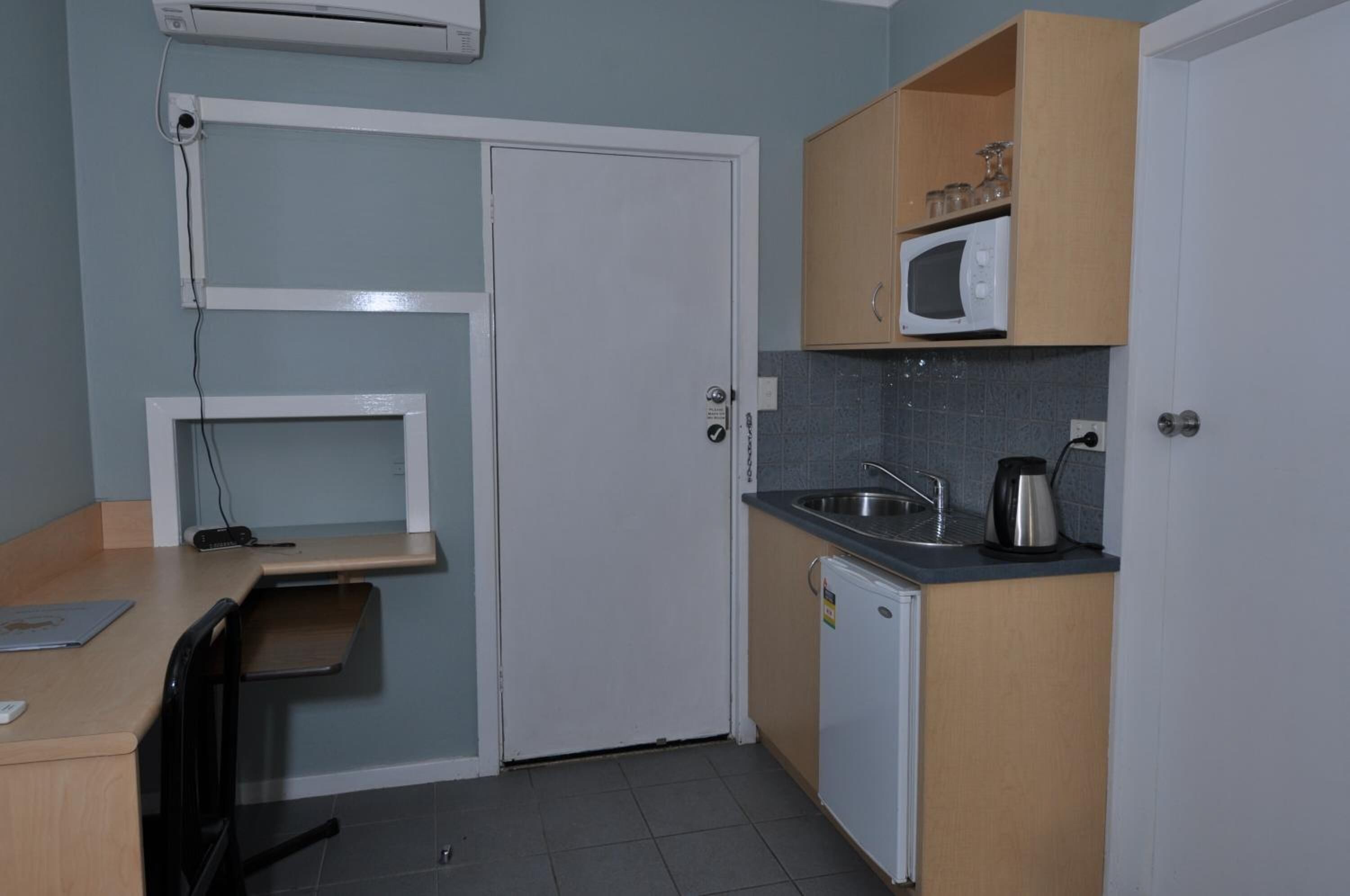 A compact kitchenette with a microwave, sink, and a small refrigerator.