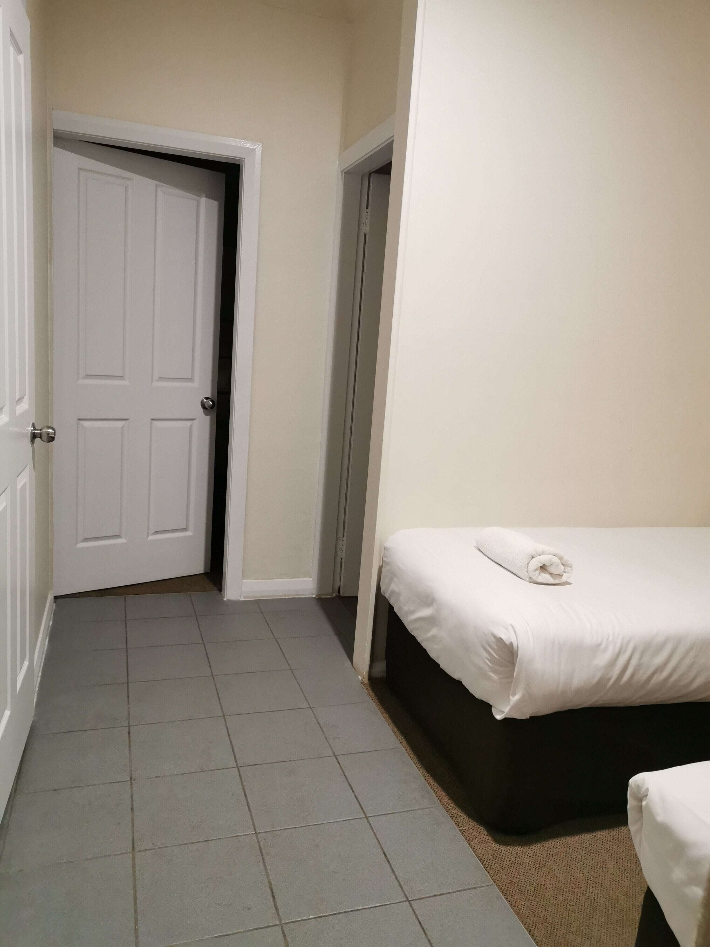 Habitación de hotel con cama, puerta y suelo de baldosas.