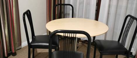 Una habitación con una mesa redonda y cuatro sillas negras.