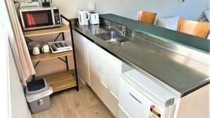 Une petite cuisine équipée d’un four à micro-ondes, d’un grille-pain et d’une machine à café.