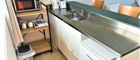 Una kitchenette compacta con microondas, tostadora y cafetera.