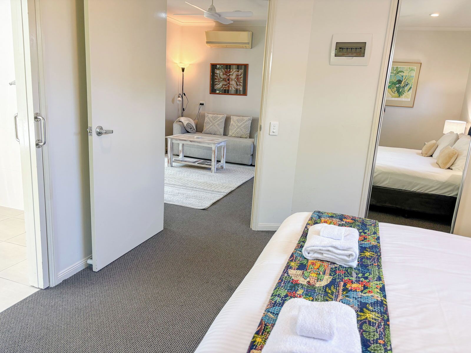 A hotel room with a bed, a small table, a sofa, and a mirror.