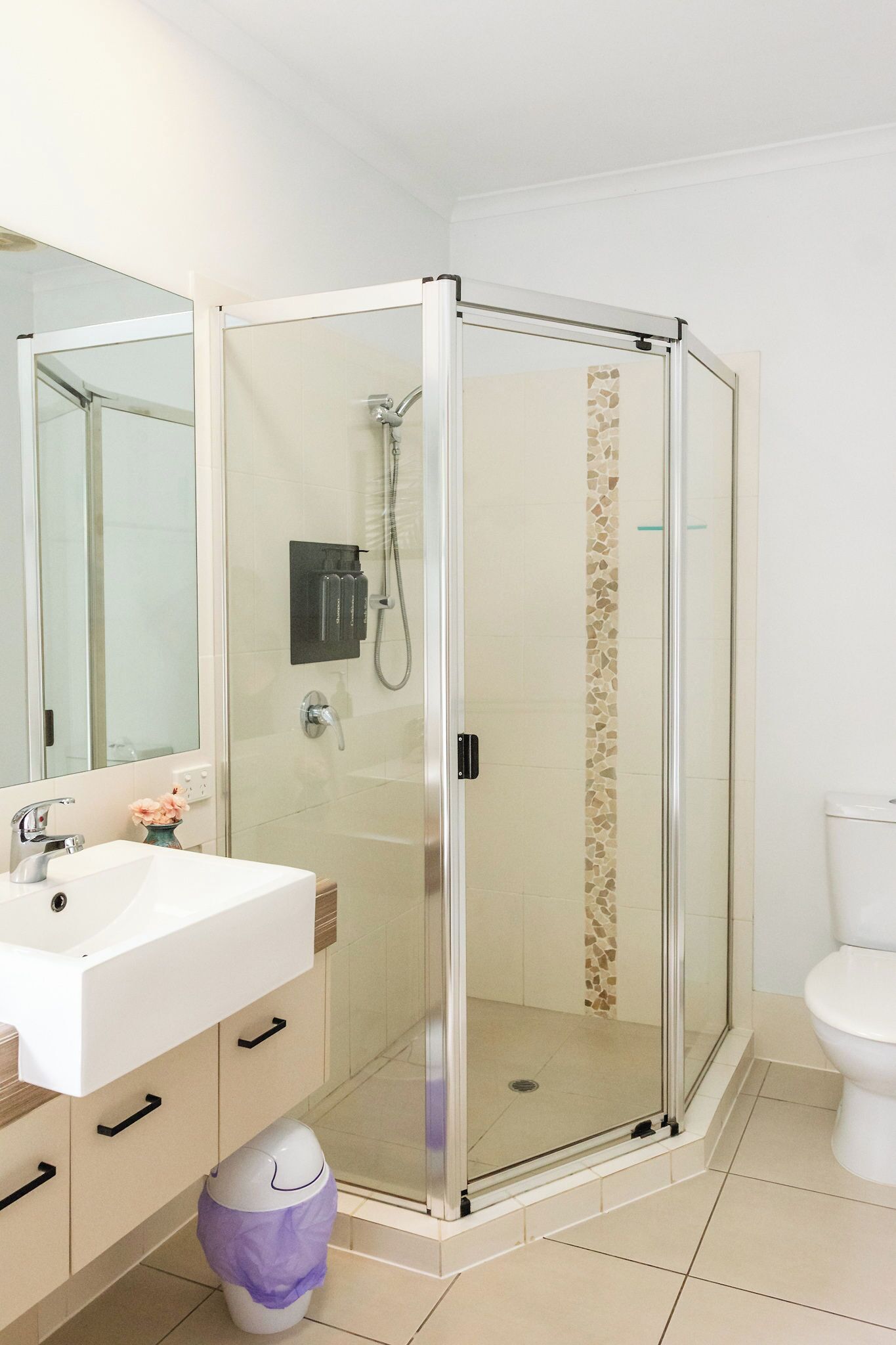 A modern bathroom with a glass-enclosed shower, a white sink, and a toilet.
