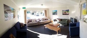 A spacious lounge with a sofa, armchairs, a coffee table, and a TV.