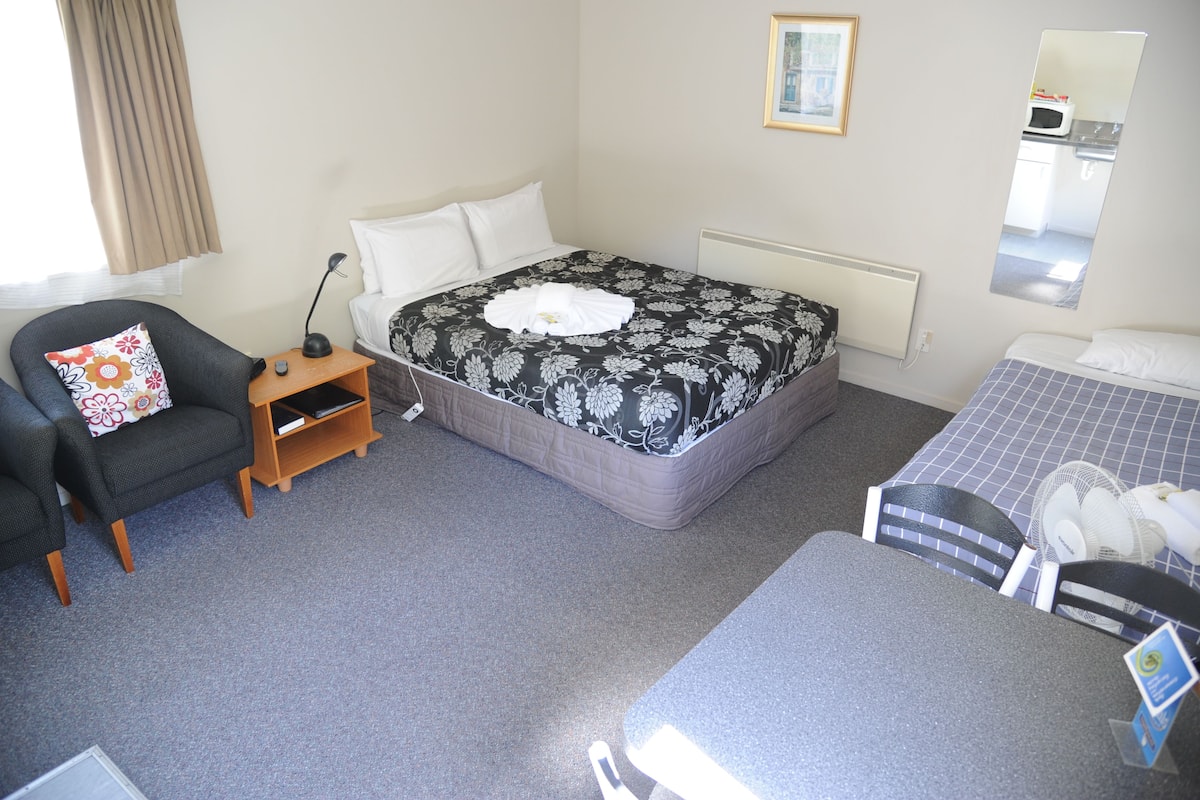 Ein Hotelzimmer mit einem Bett, einem Sessel, einem Schreibtisch und einem kleinen Tisch.