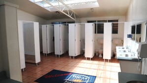 A hotel bathroom with multiple stalls, a sink area, and a welcome mat. - Blenheim Bridges Holiday Park (Blenheim)