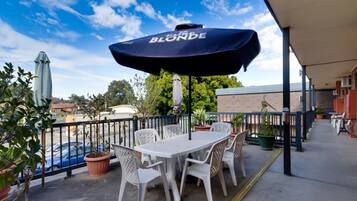Relax under the shade of a large umbrella, surrounded by lush potted plants, and enjoy a meal at a table set for two.