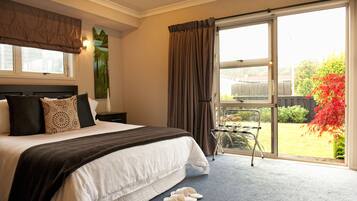 Un dormitorio con una cama grande, una ventana con cortinas y vistas a un jardín.