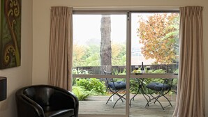 A room with a sliding glass door leading to an outdoor deck with two chairs and a table. - B&B @ the Redwoods (Rotorua)