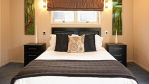 A bedroom with a large bed, two bedside tables, a window with blinds, and two wall-mounted lamps. - B&B @ the Redwoods (Rotorua)