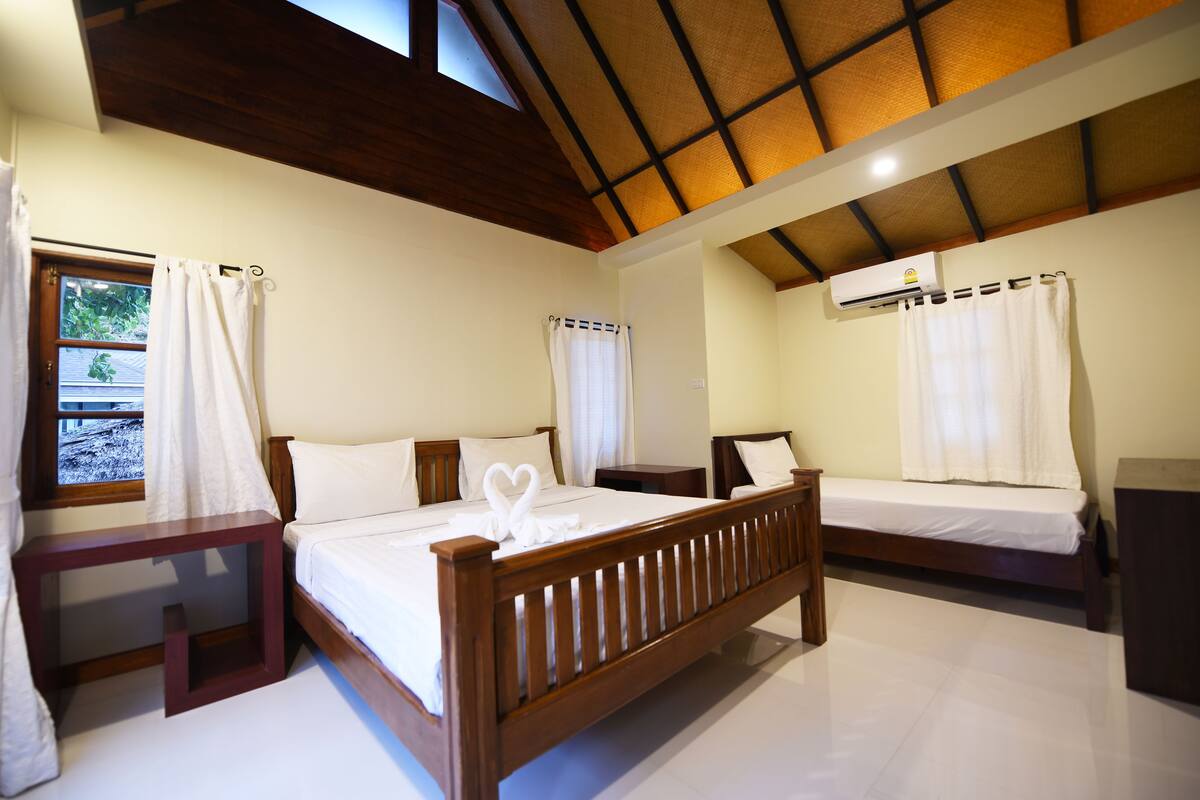 A hotel room with two wooden beds, white bedding, and a wooden headboard.