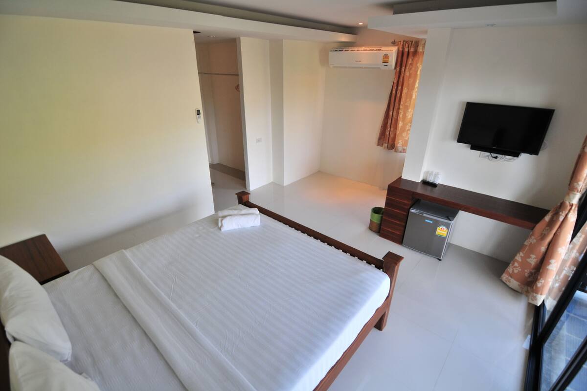 A hotel room with a bed, a desk, a television, and a window with curtains.