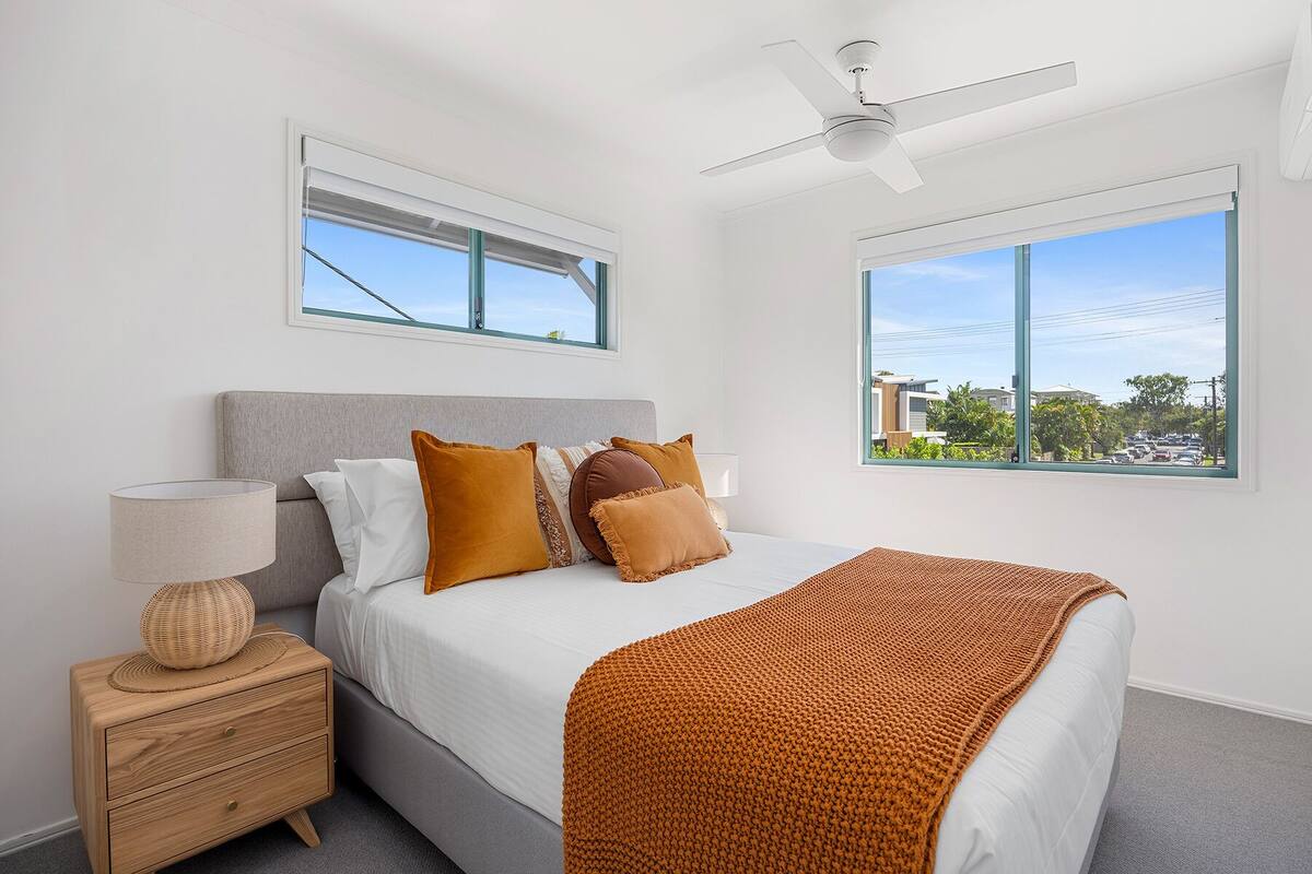 A bedroom with a bed, nightstand, lamp, and a ceiling fan.