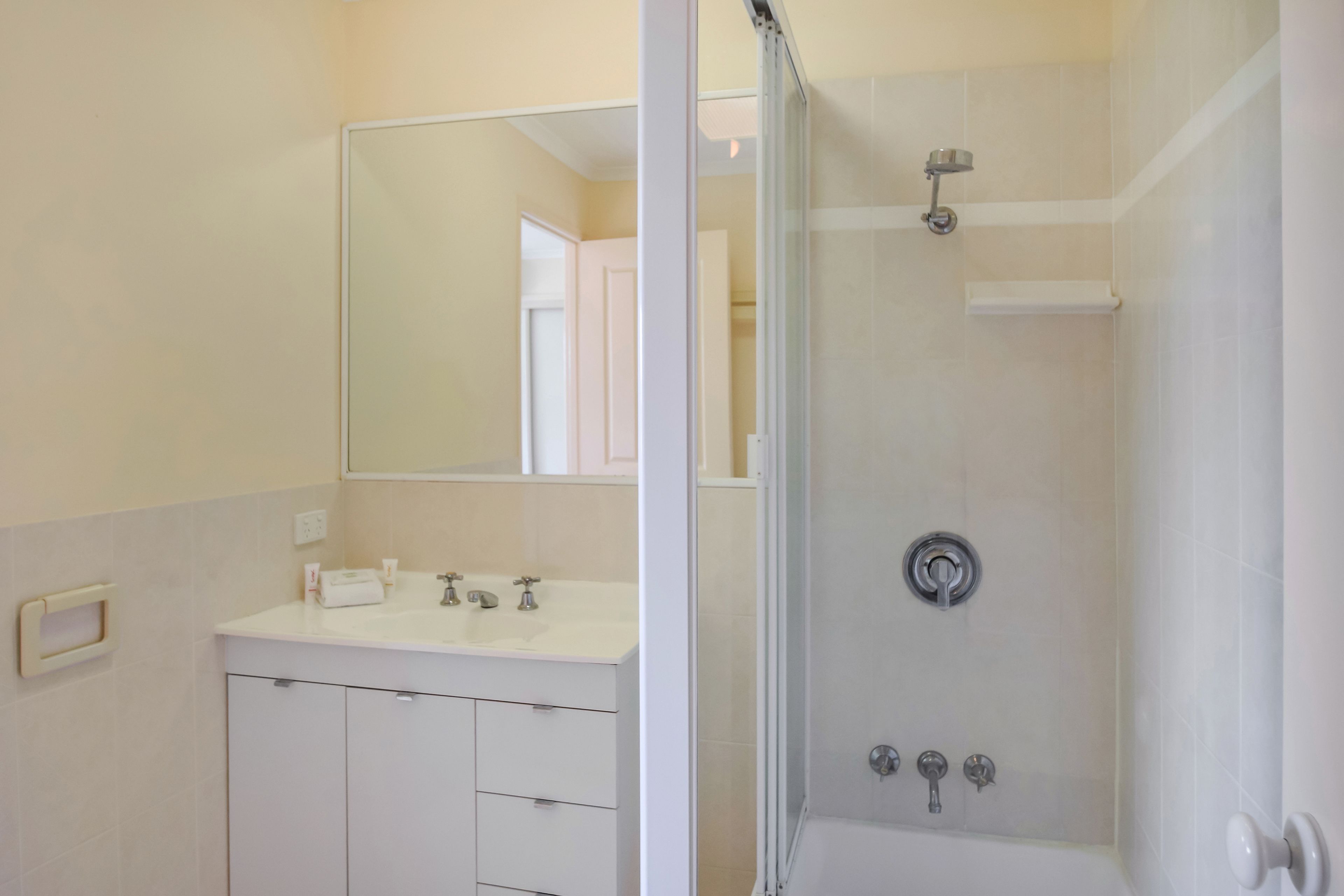 A bathroom with a white vanity, a mirror, a shower with a glass door, and a toilet.