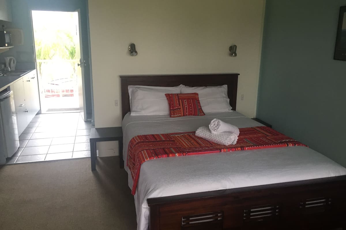 A hotel room with a bed, a small desk, and a view of the outside.