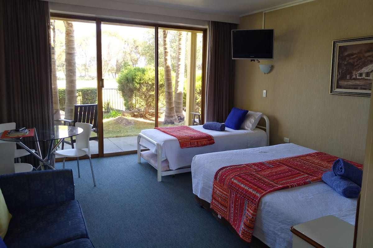 A hotel room with two beds, a TV, a desk, and a chair.