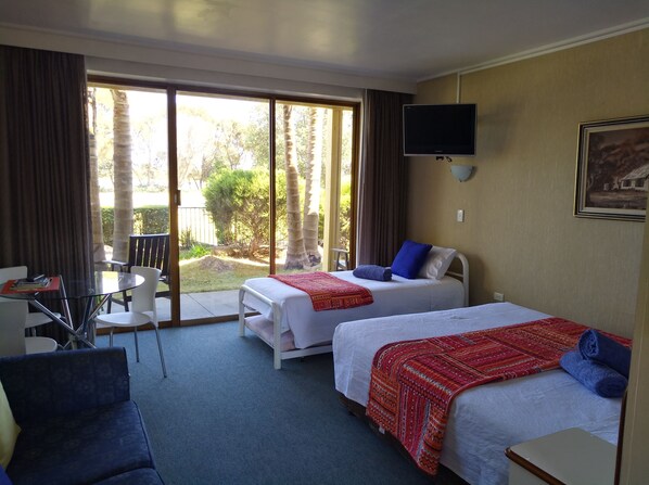 A hotel room with two beds, a TV, a desk, and a chair.