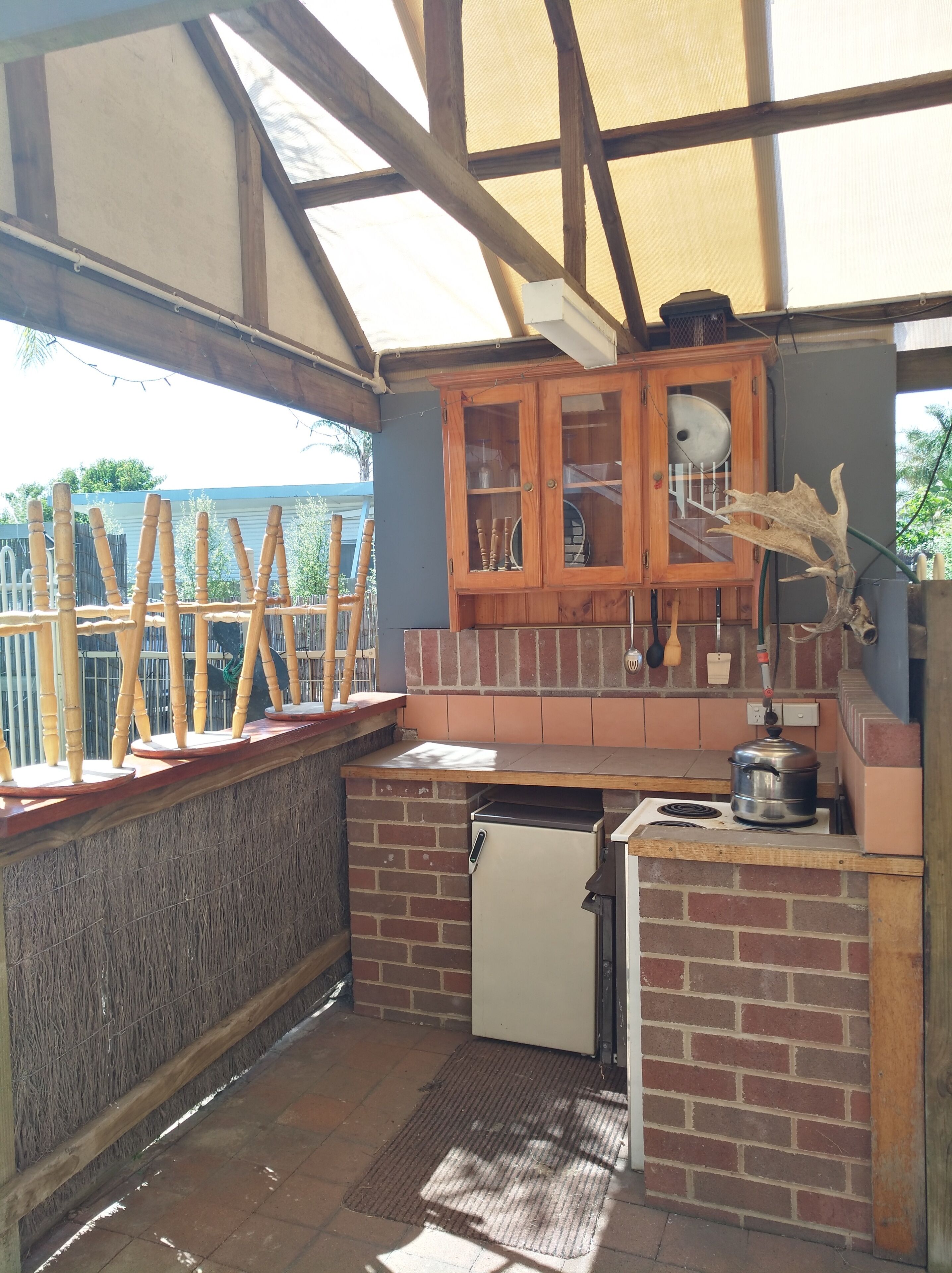 A small, enclosed kitchen with a brick wall, wooden cabinets, and a small refrigerator.