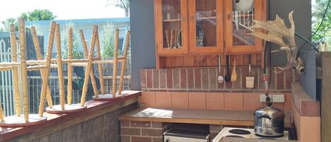 Una cocina pequeña y cerrada con pared de ladrillo, armarios de madera y un refrigerador pequeño.