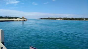 A waterfront view with a pier, calm water, and a distant shoreline with trees and buildings.