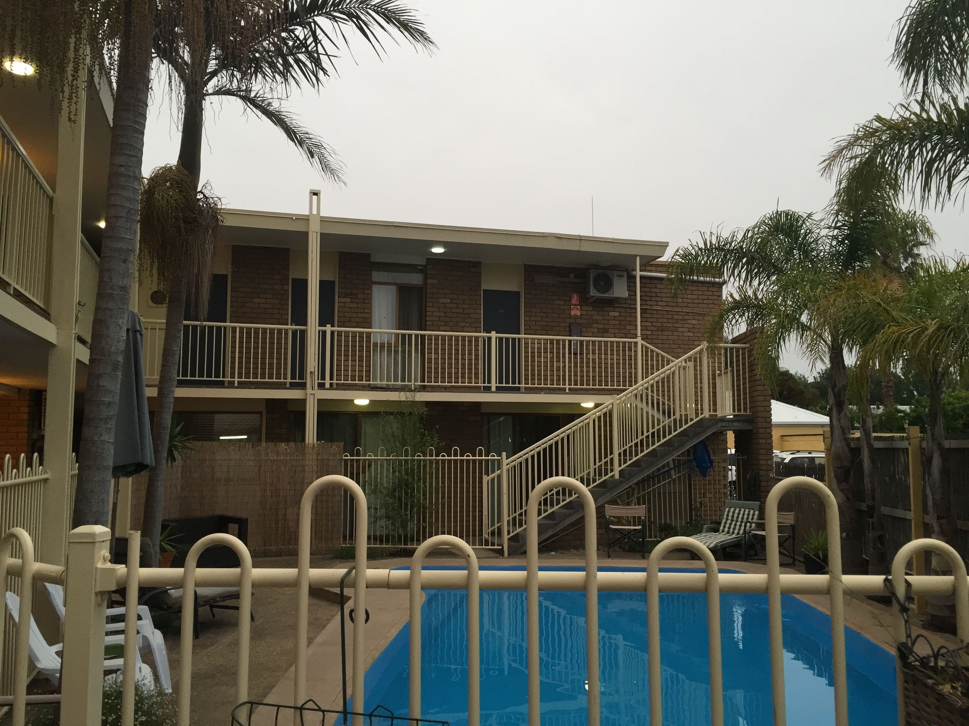 A two-story building with a pool area, including a staircase and railings.