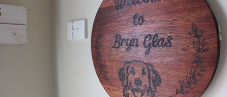 A round wooden sign with a dog engraving and the text "Welcome to Bryn Glas."