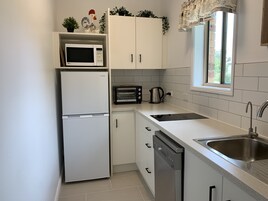 A compact kitchen with white cabinets, a built-in microwave, a toaster, and a dishwasher.