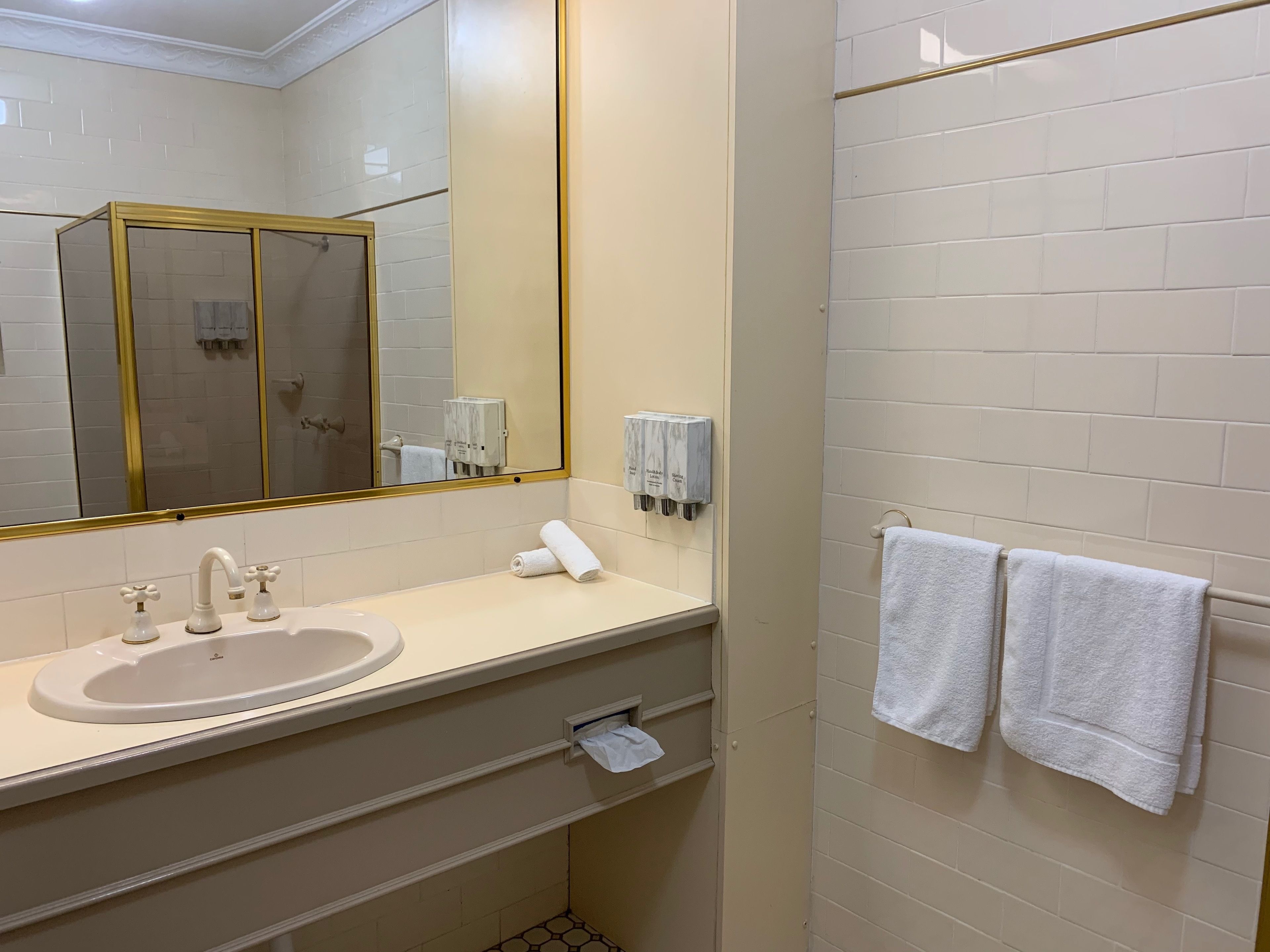 Un baño con lavabo, espejo, toallero y zona de ducha.