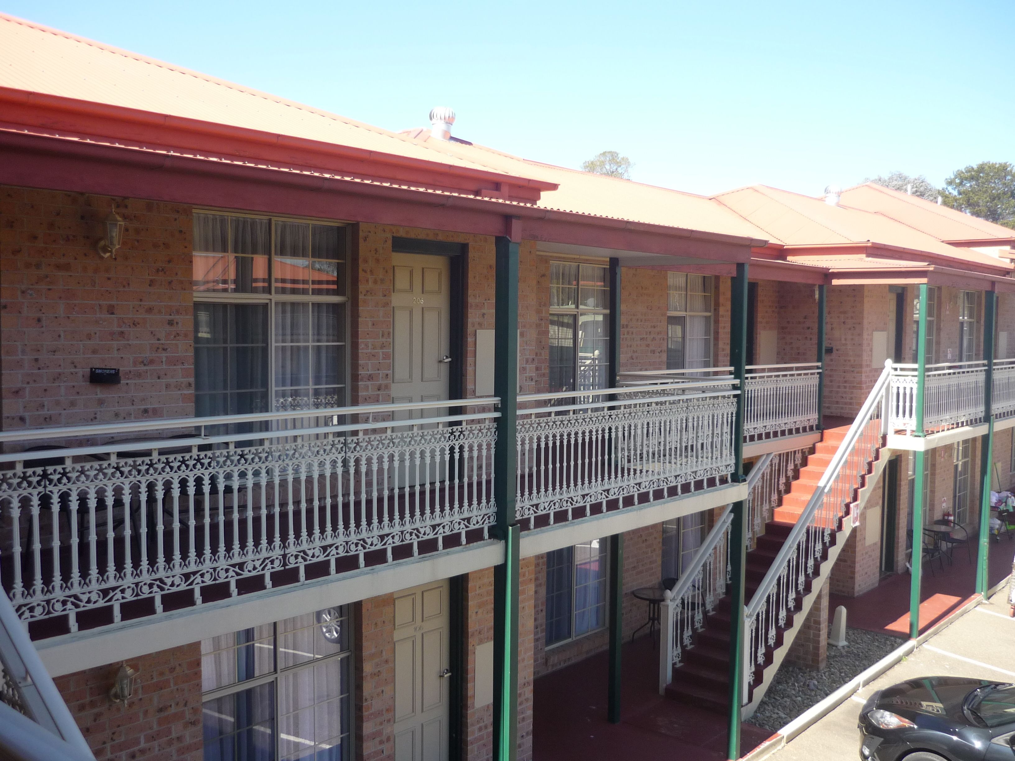 A multi-story building with balconies, brick walls, and a red roof.