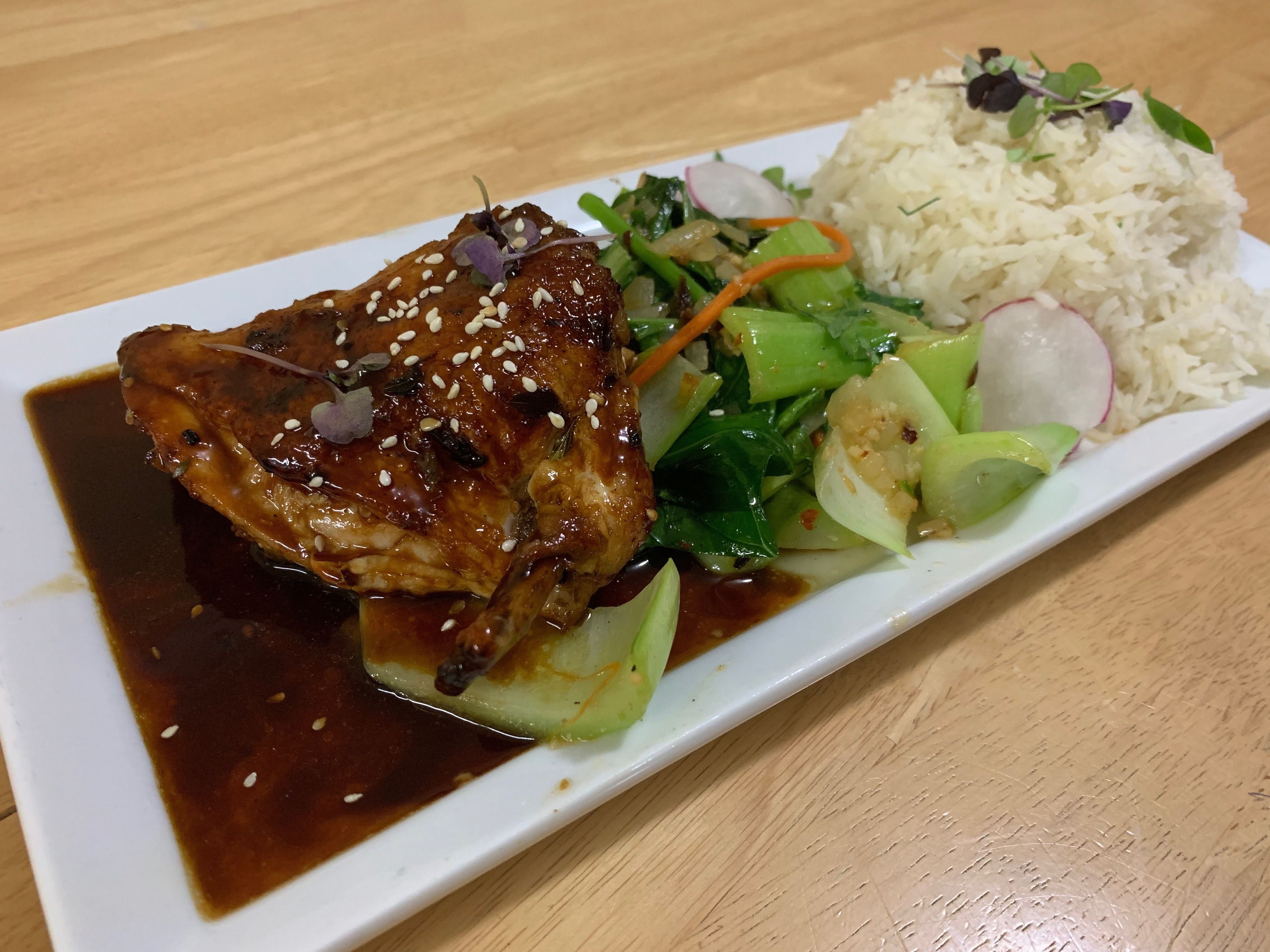 A plate with a piece of meat, rice, and vegetables.