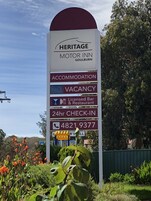 Señal de Heritage Motor Inn en Goulnburn, indicando alojamiento, sin habitaciones disponibles, bar y restaurante con licencia, recepción las 24 horas y un número de contacto.