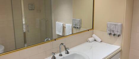 Un baño con un espejo grande, un lavabo y una cabina de ducha de vidrio.
