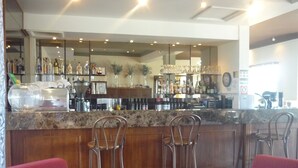 A bar area with a marble countertop, metal bar stools, and a variety of bottles and glasses. - Heritage Motor Inn Goulburn (Goulburn)