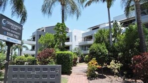 A modern building with a sign indicating Grangewood Court, holiday apartments, and a contact number.