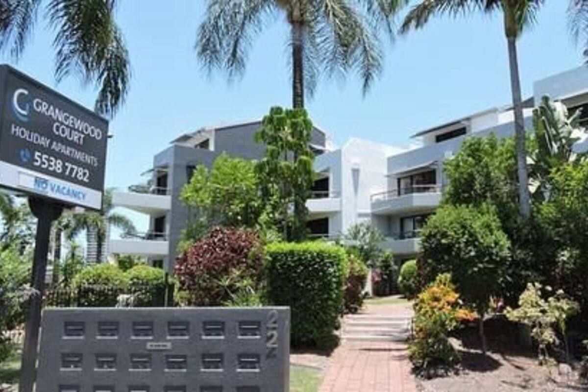 A modern building with a sign indicating Grangewood Court, holiday apartments, and a contact number.