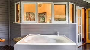 Un baño moderno con una bañera grande, un cuenco de vidrio con piedras y vistas a través de ventanas con vidrio esmerilado.