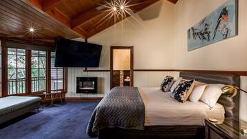 A bedroom with a bed, bedside table, lamp, TV, and a painting on the wall.