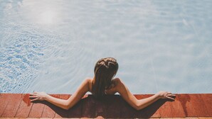 Una persona sentada al borde de una piscina con vista despejada al agua.