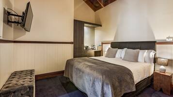 A bedroom with a bed, bedside table, and a television mounted on the wall.
