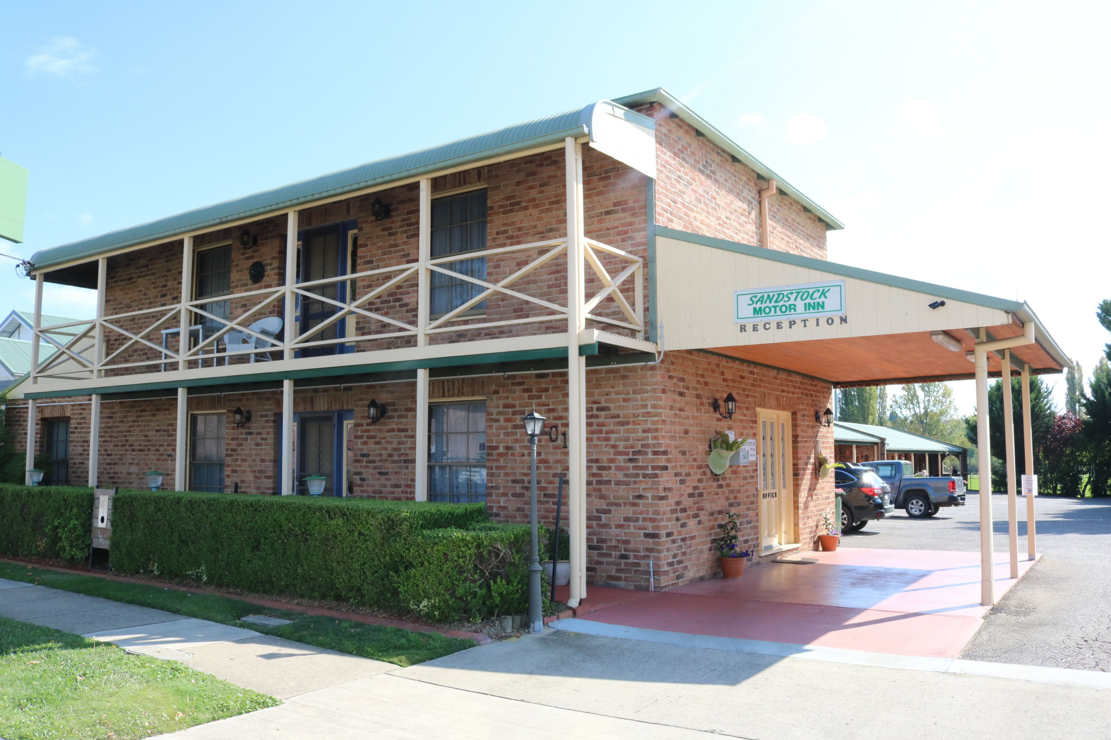 A brick building with a covered reception area, a balcony, and a parking lot.