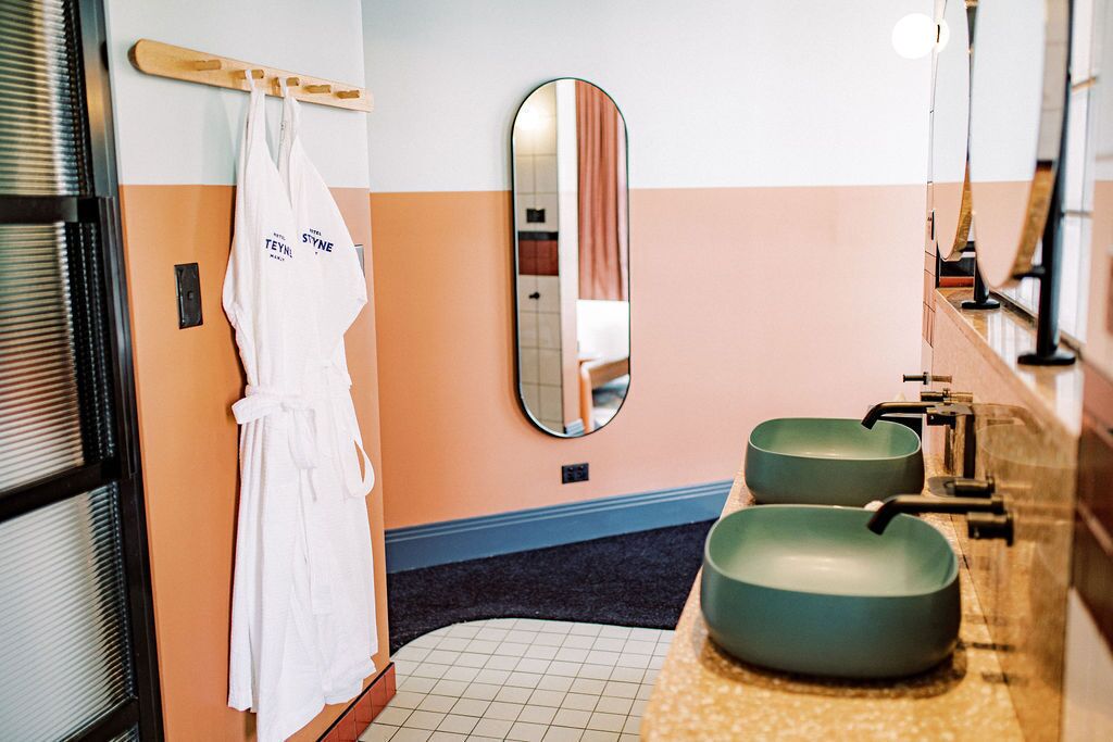 A bathroom with two sinks, a mirror, and a robe hanging on a rack.