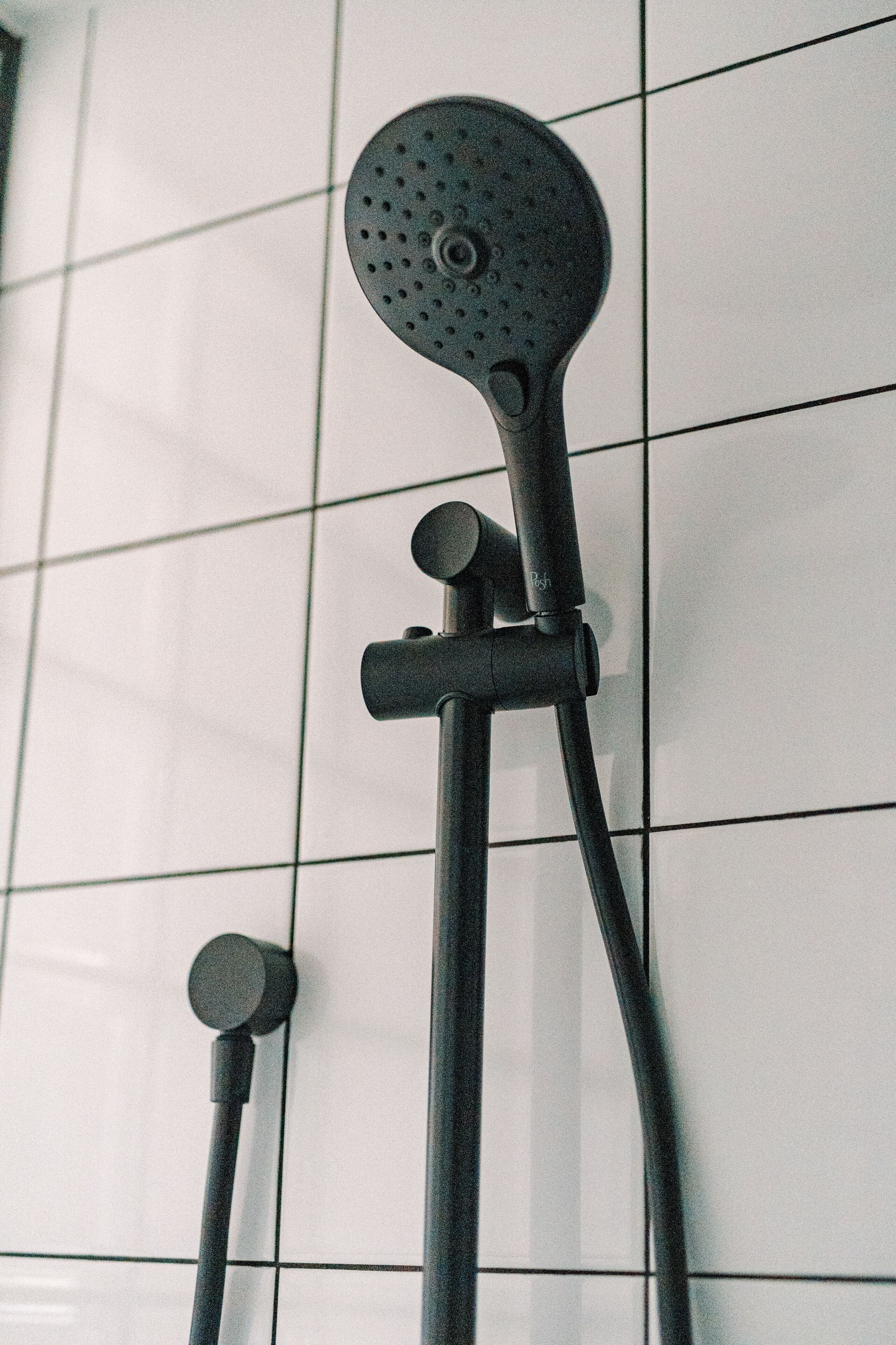 A showerhead mounted on a tiled wall.